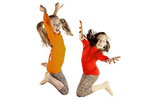 two girls jump in the air smiling